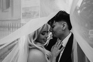 Black and white romantic portrait of bride and groom sharing tender moment under veil.