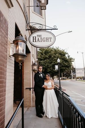 Bride and groom posing outside The Haight wedding venue beside vintage gas lanterns and iron railing.