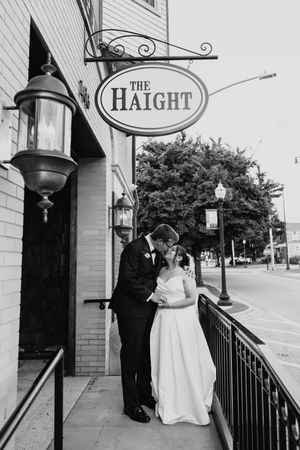 Black and white photo of bride and groom sharing a tender moment under The Haight venue sign.