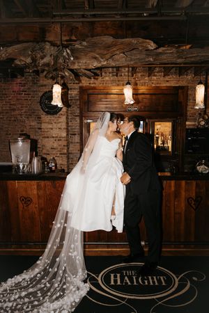 Bride and groom kissing at The Haight bar with exposed brick walls and warm Edison lighting.