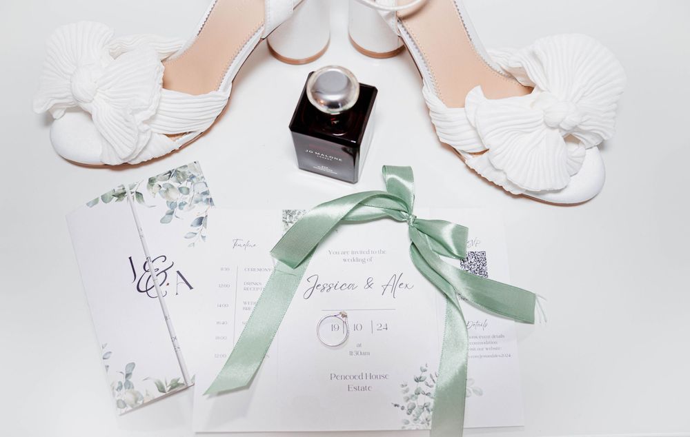 Wedding stationery and accessories arranged on white background with mint green ribbon accents.