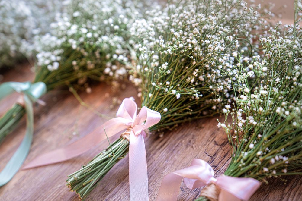 Delicate baby's breath flower bouquets with pink and white ribbons on wooden surface.