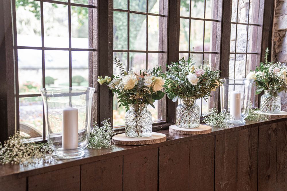 Elegant floral centerpieces line a rustic windowsill at a wedding reception.