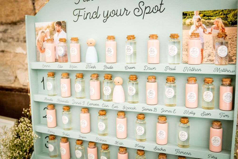 Mint green display rack filled with numbered mason jars for wedding seating.