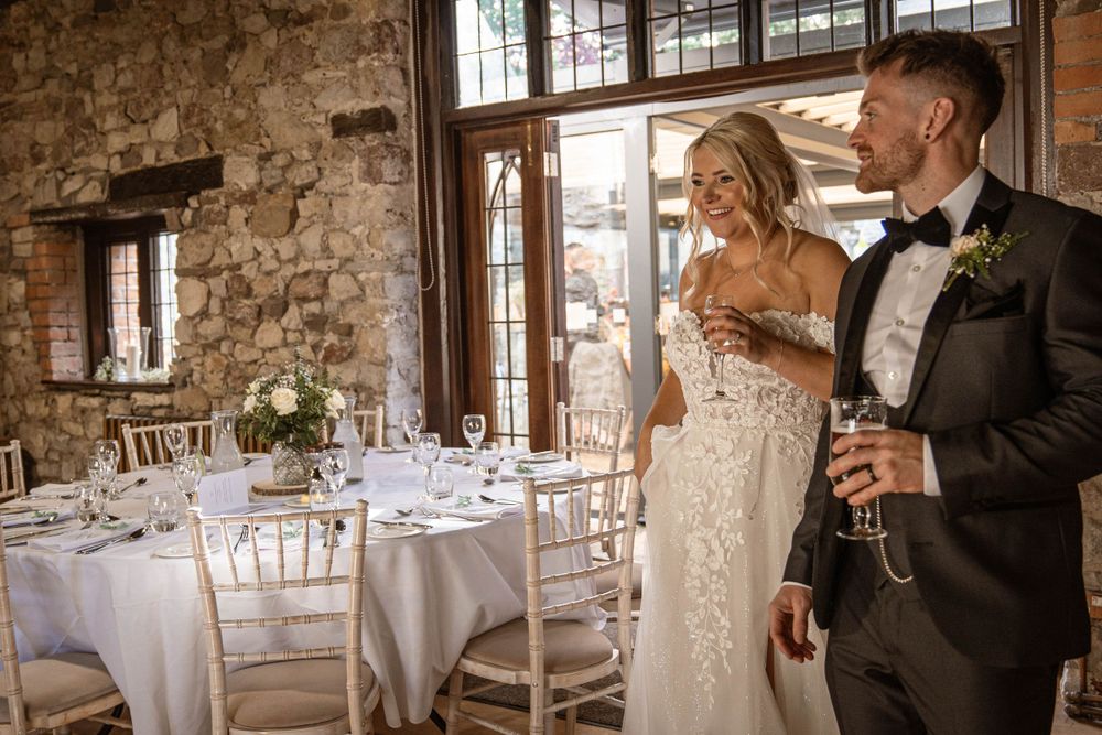 Couple enjoying champagne in rustic stone venue with elegant table settings.