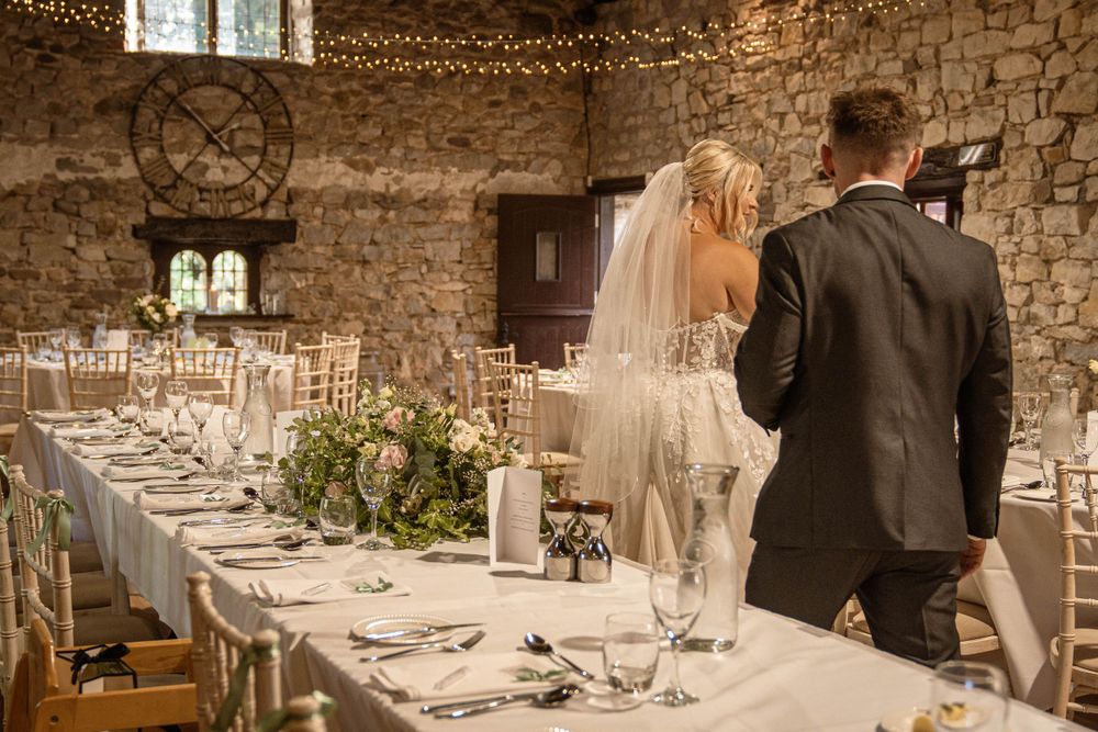 Elegant wedding reception setup in rustic stone venue with fairy lights.