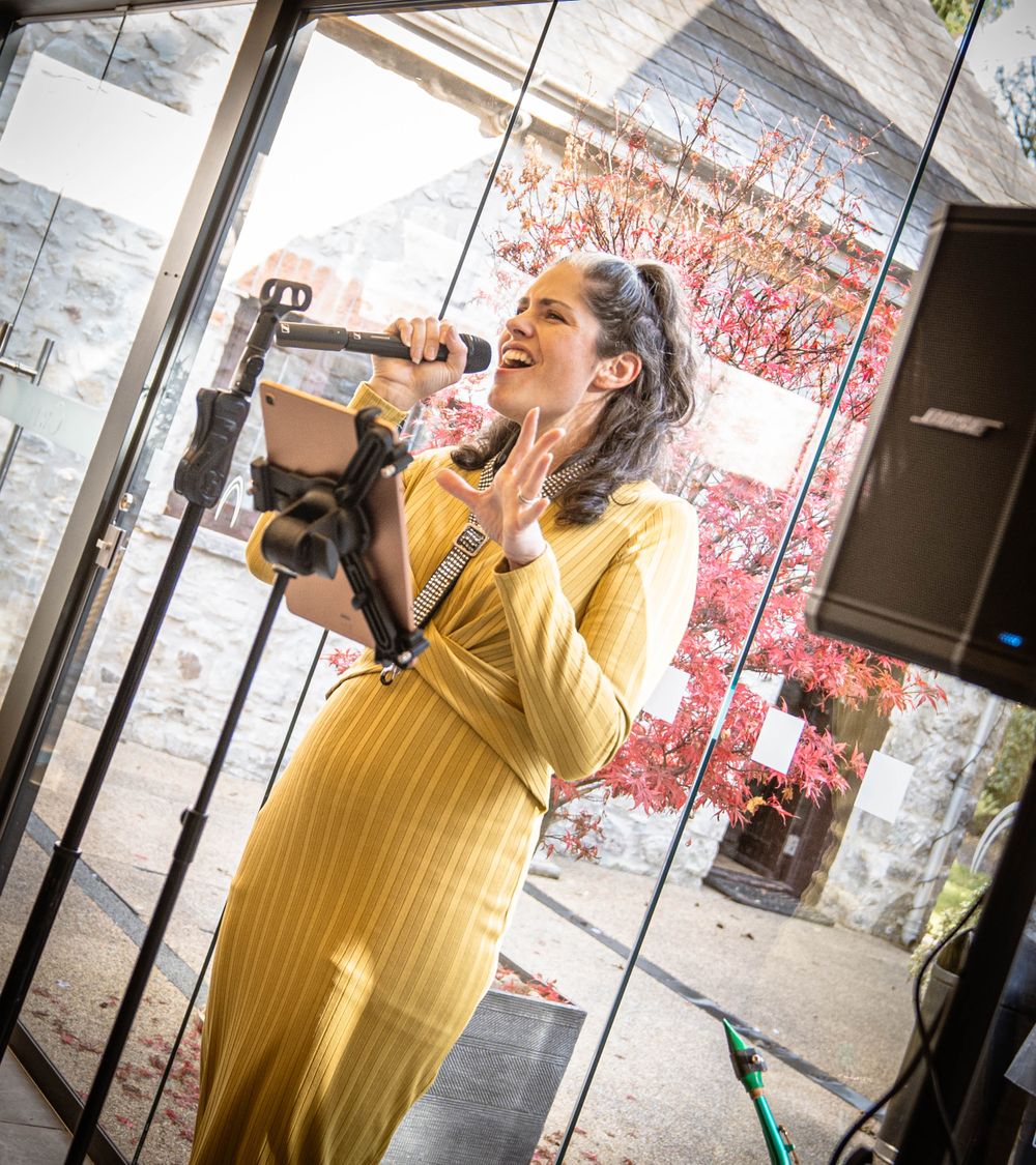 Singer performing passionately in yellow dress at wedding venue.