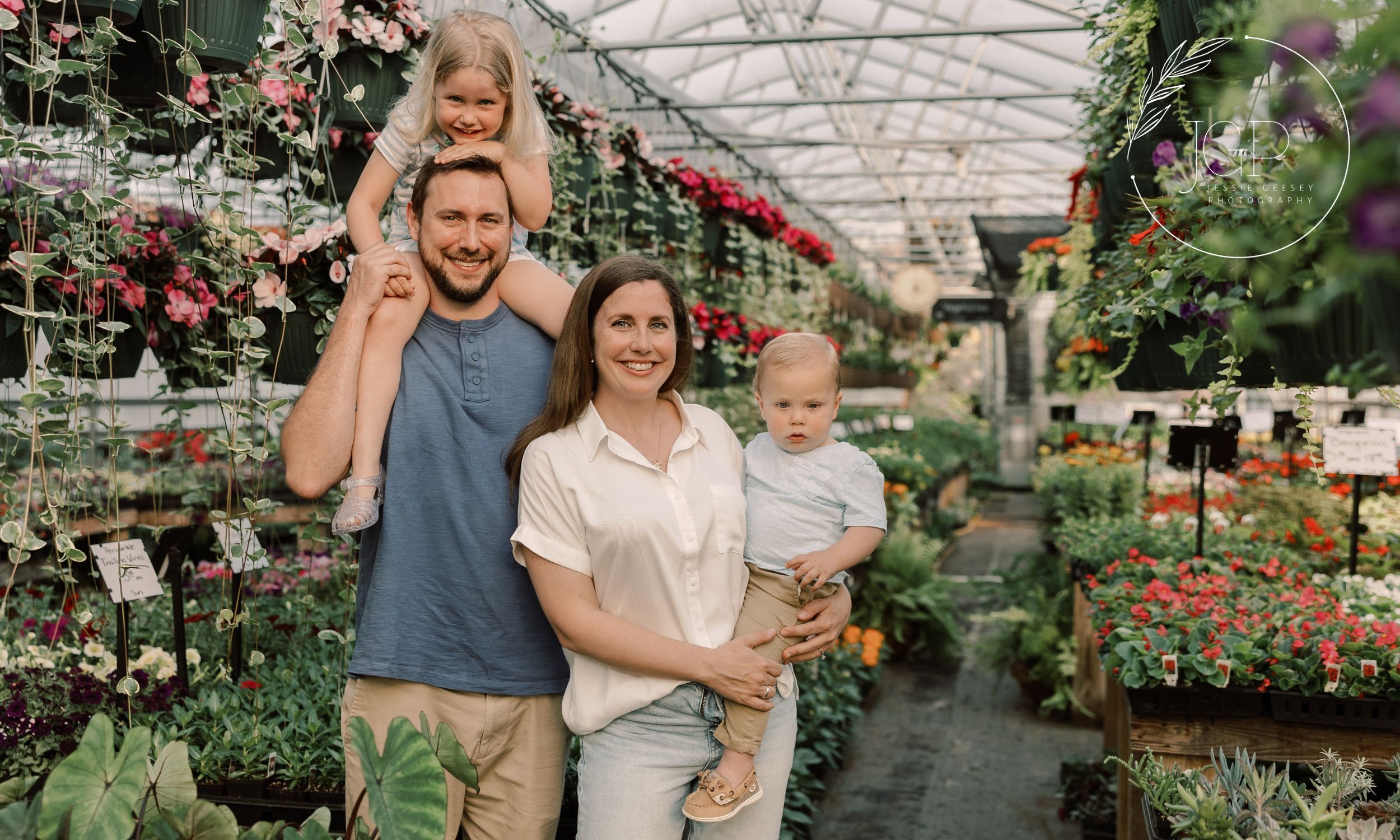 A man, woman and two children smiling at the camera in a greenhouse