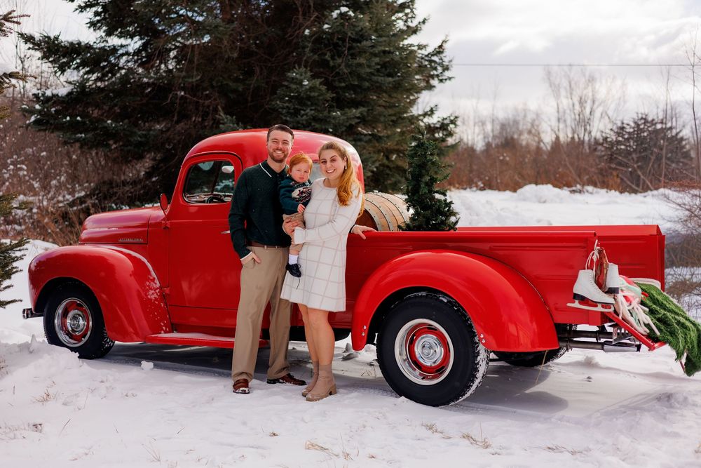 A bright red vintage car is photographed in multiple snowy winter scenes during what appears to be a holiday photoshoot.