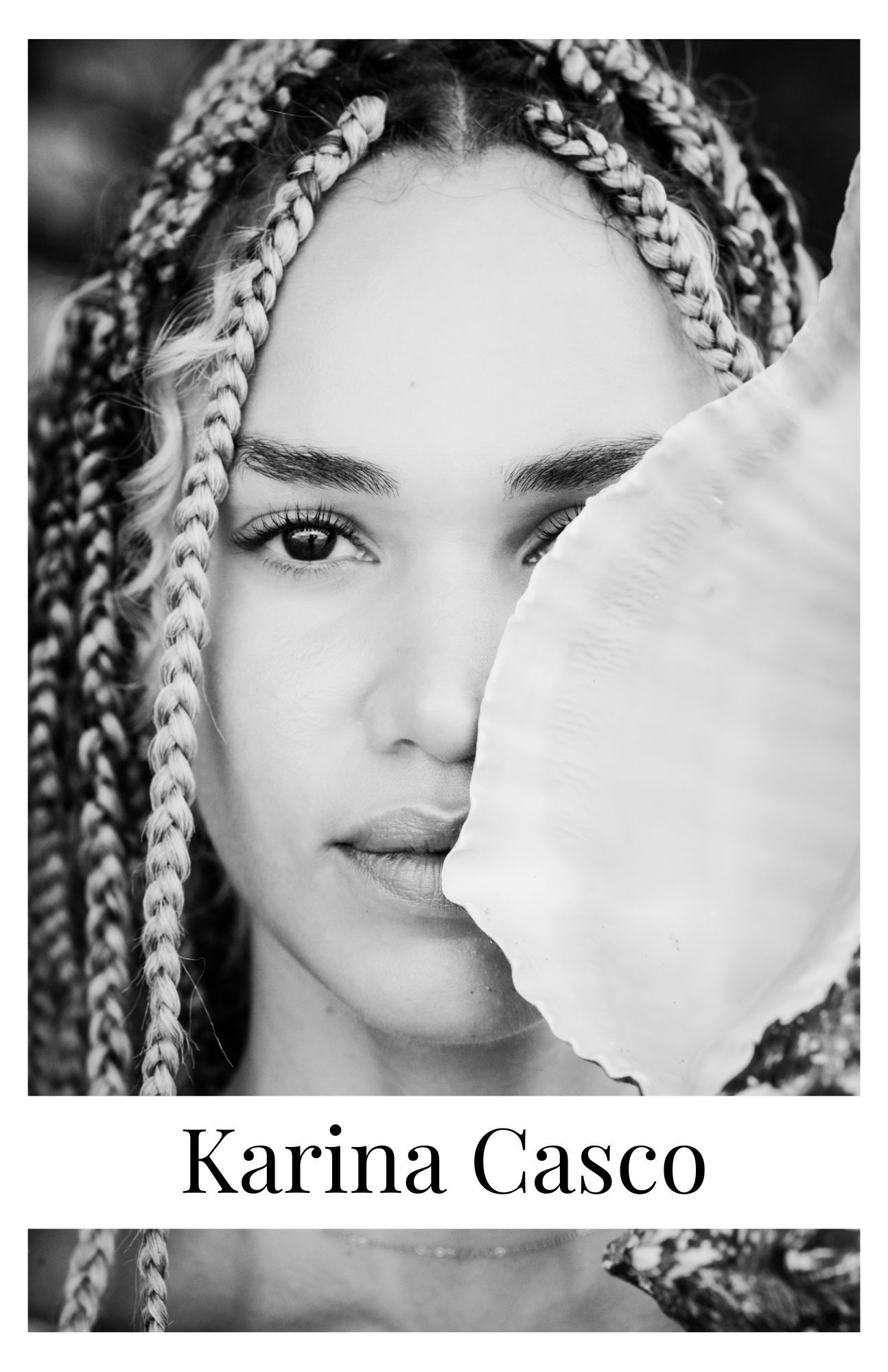 Black and white portrait photograph showing a person with striking box braids and graceful features in an artistic pose.