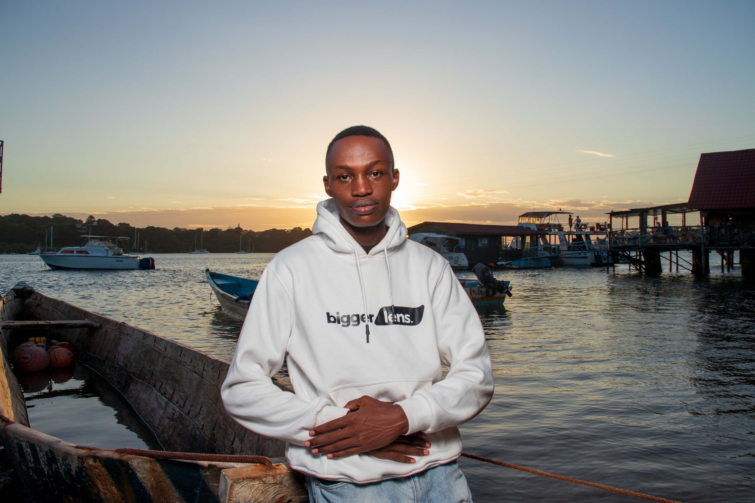 A young man with hood at boat dock area in a sunset