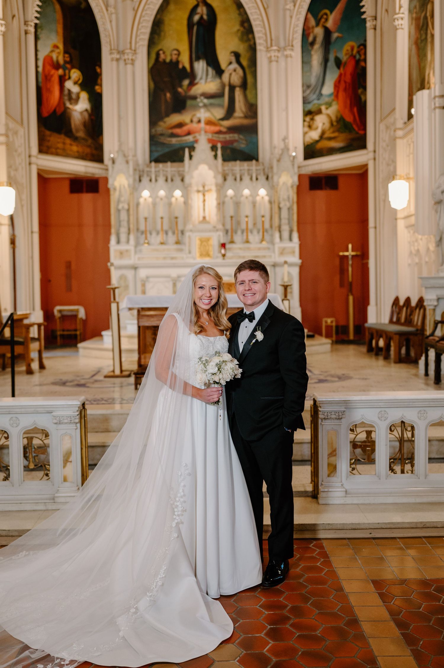 A bride and groom share a romantic moment in a beautiful ornate church with gothic architecture and religious artwork.
