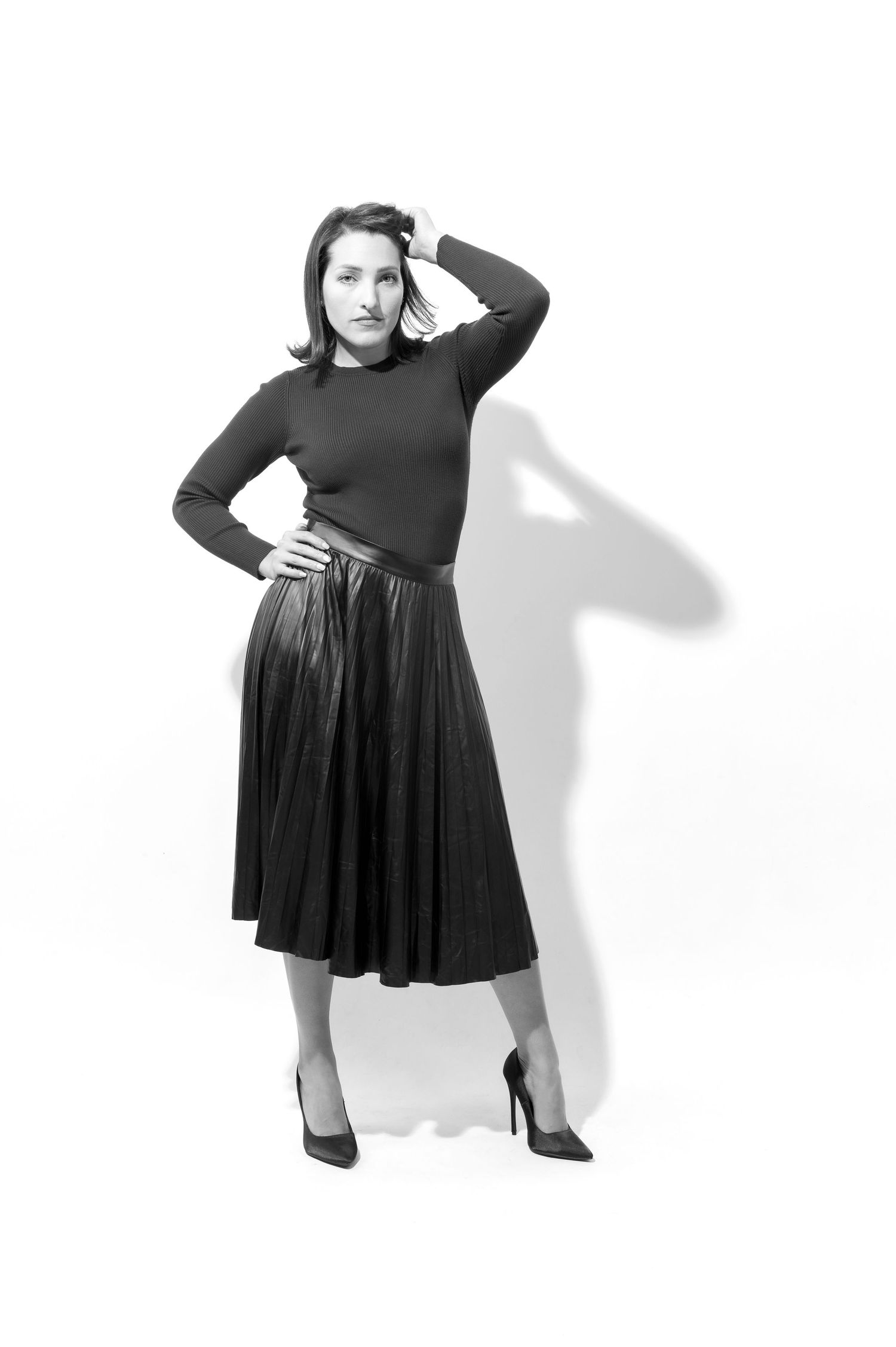 A person in a black dress strikes four different poses against a white background, showing the dress from various angles.