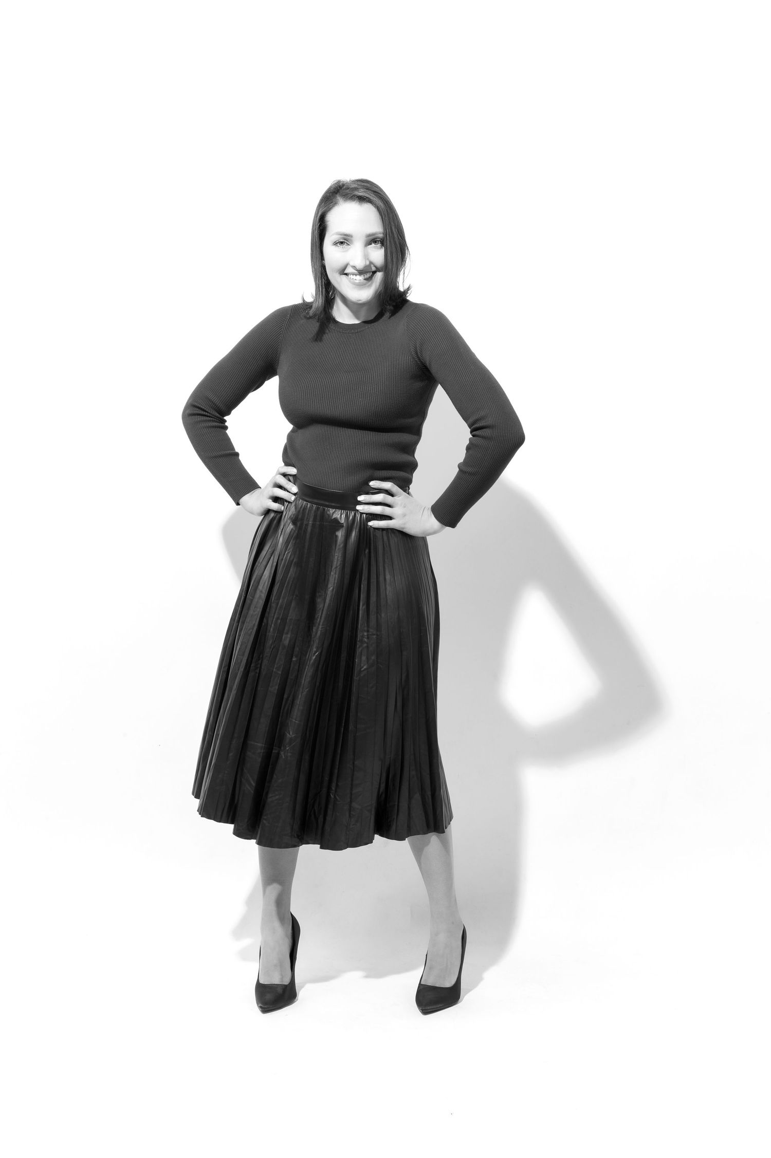 A figure in a black turtleneck and pleated skirt poses in four similar standing positions against a white background.