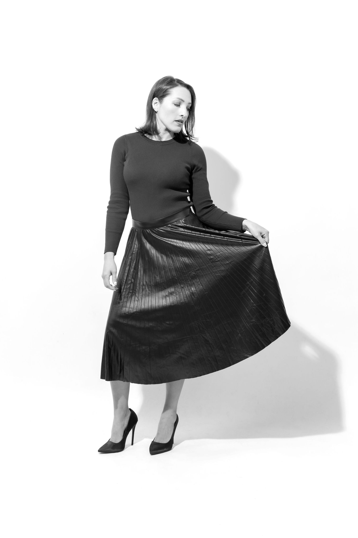 A figure in a black long-sleeved dress and heels strikes different poses against a white background.