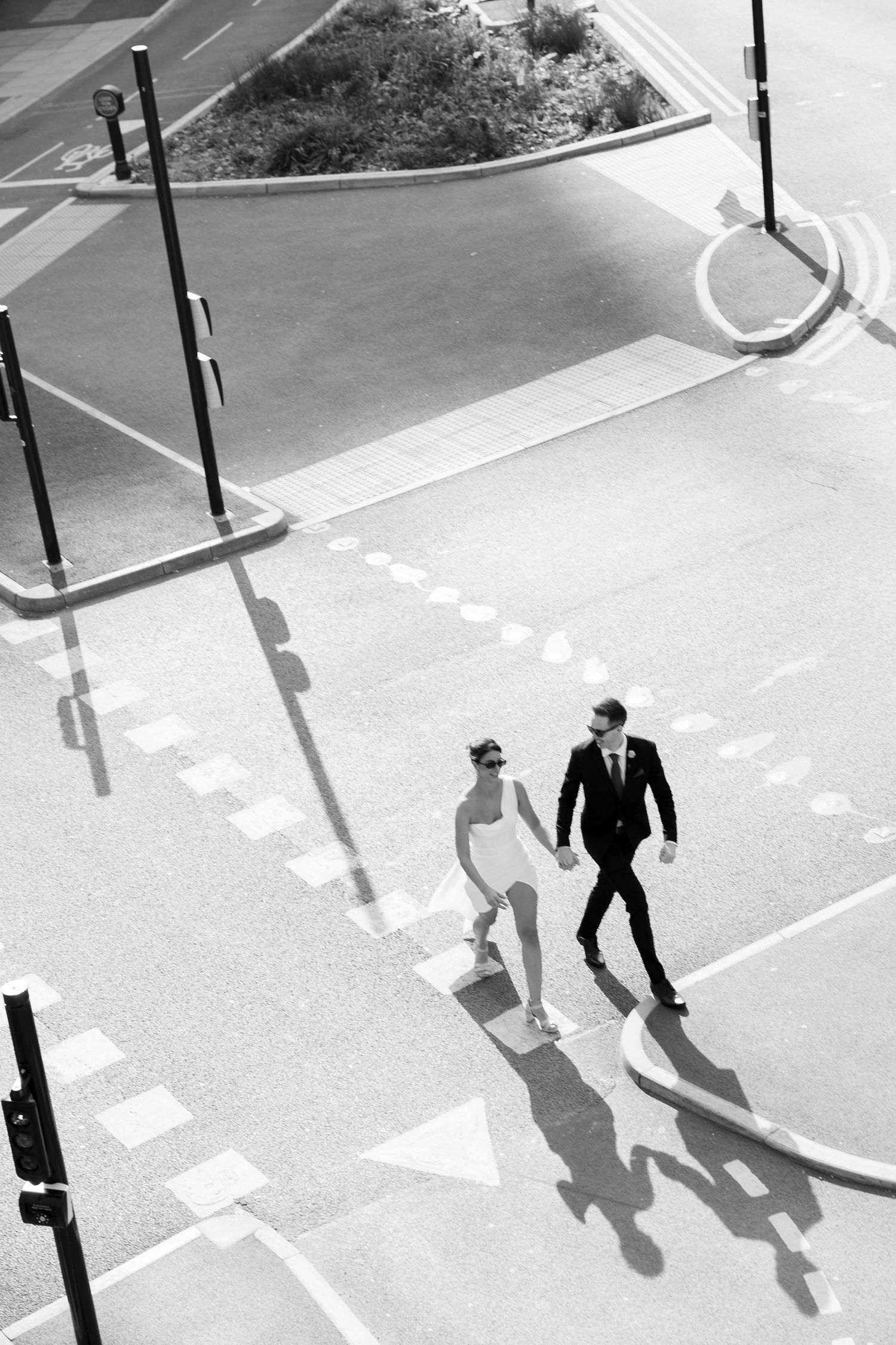 Couple poses on urban rooftop with city skyline and elevated train tracks in black and white wedding photo.