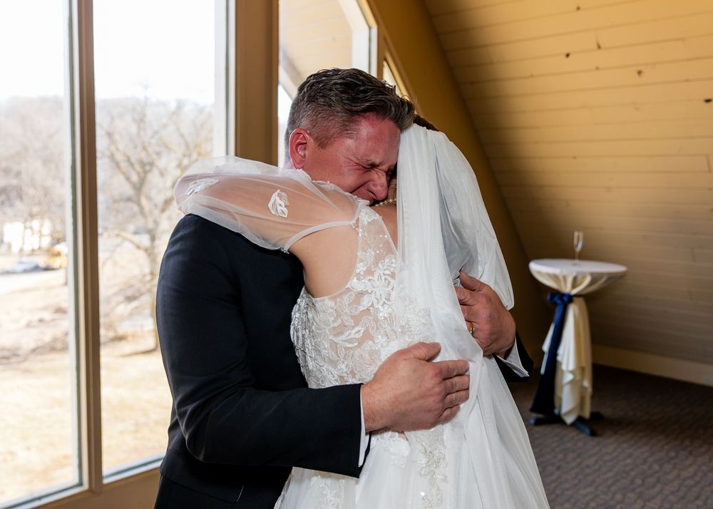 Emotional bride and groom sharing a heartfelt hug during first look at wedding venue.