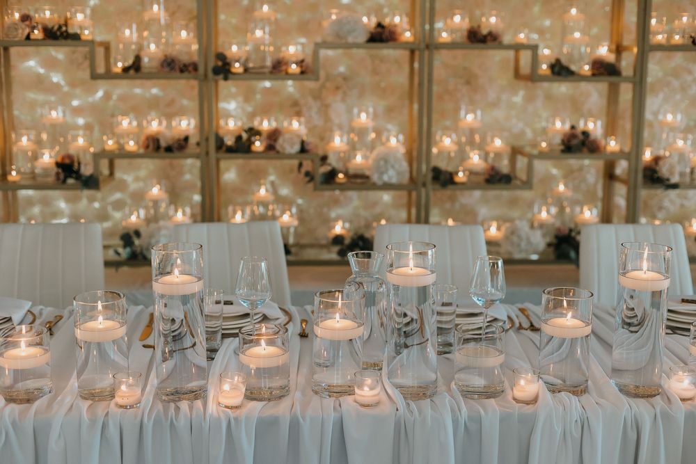 Elegant wedding reception table with floating candles and glowing candlelit shelves creating a warm, romantic ambiance.