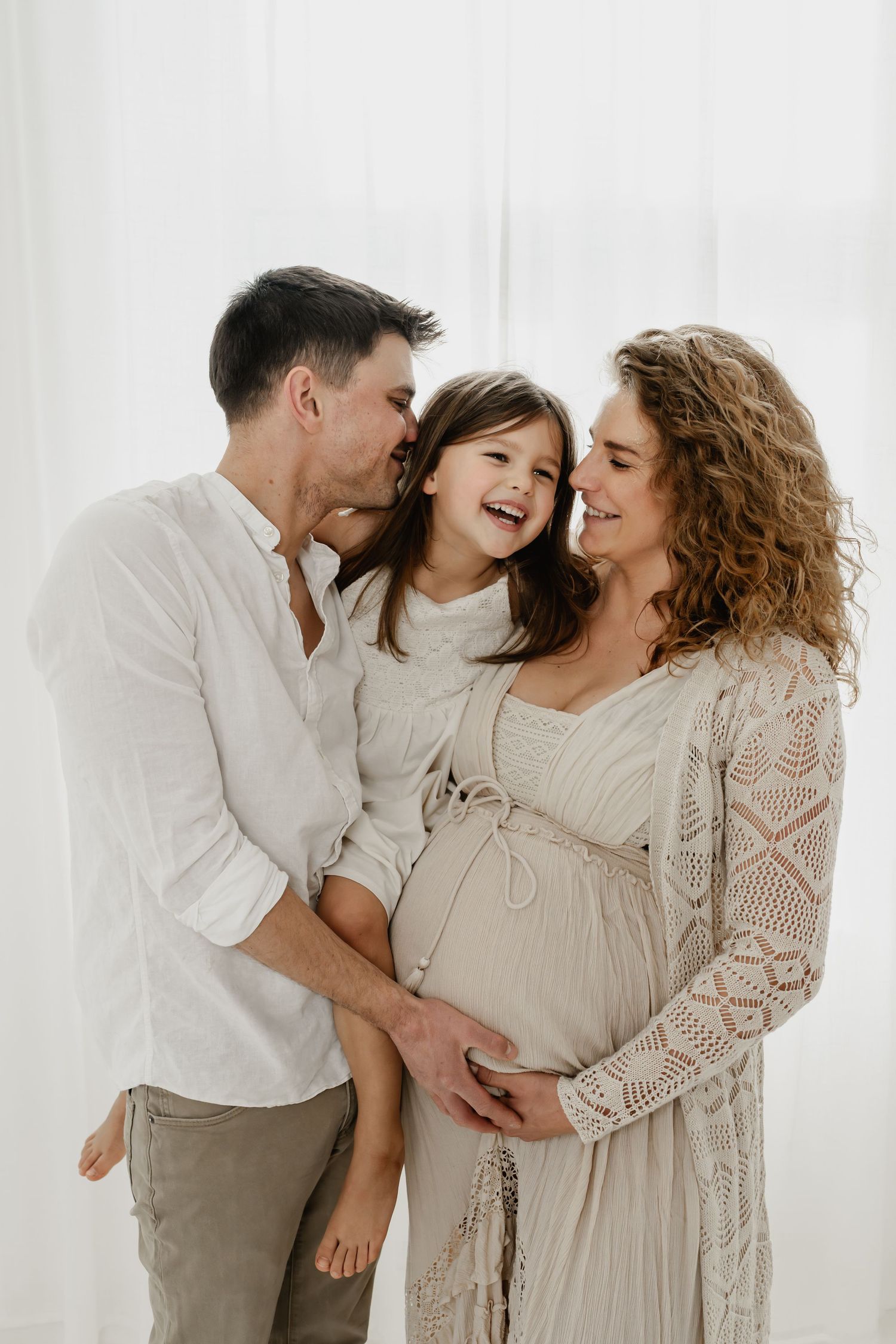 Familie lacht herzhaft beim Babybauchfotoshooting Wien mit Geschwisterkind