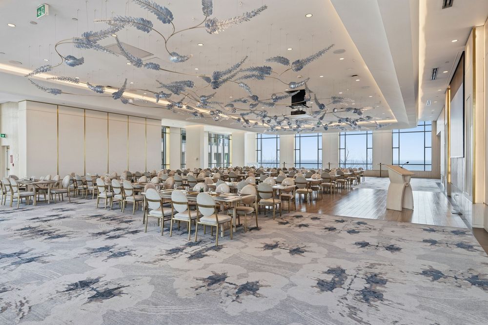 Large empty cafeteria interior with gray speckled floors, white walls, and natural lighting through windows.