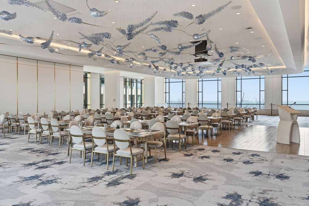 Modern office space with rows of desks and chairs under a ceiling decorated with airplane models.