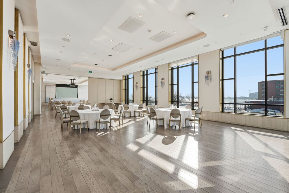 Bright open-concept office interior featuring wood flooring, white walls, and large windows with urban skyline views.