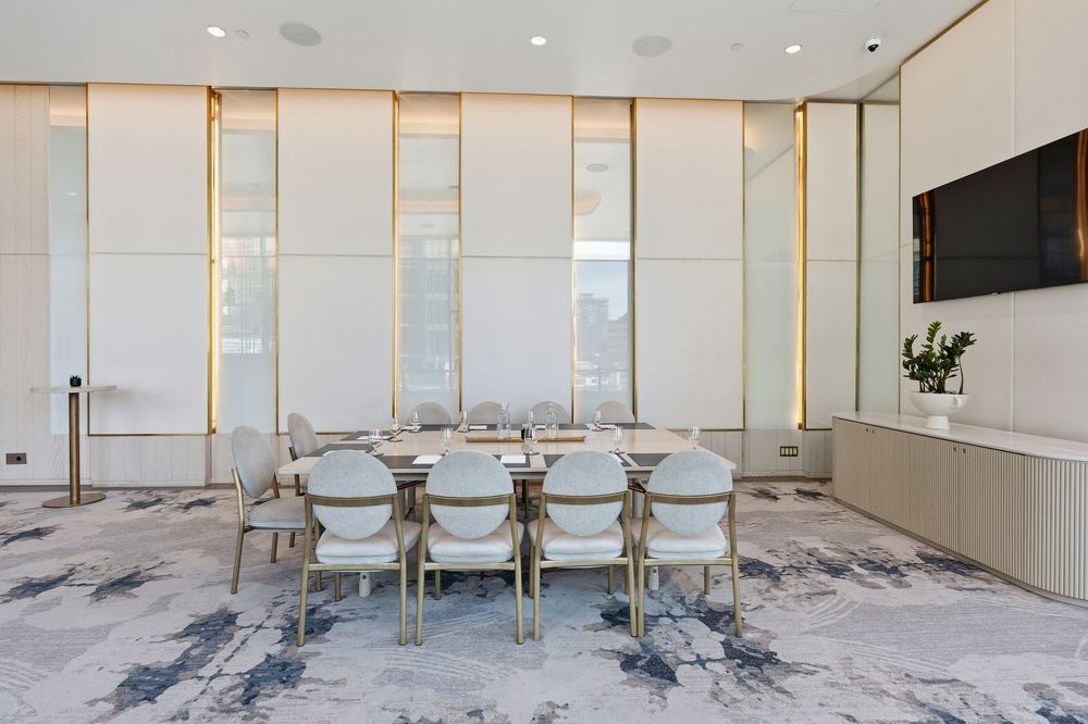 Contemporary conference room with marble flooring, white paneled walls, and metallic accents featuring sleek furniture.