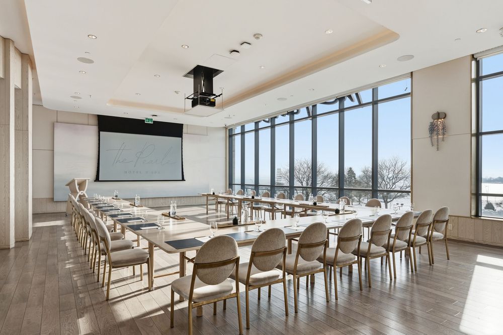 Modern conference room with panoramic windows and rows of wooden chairs arranged classroom style in a bright space.