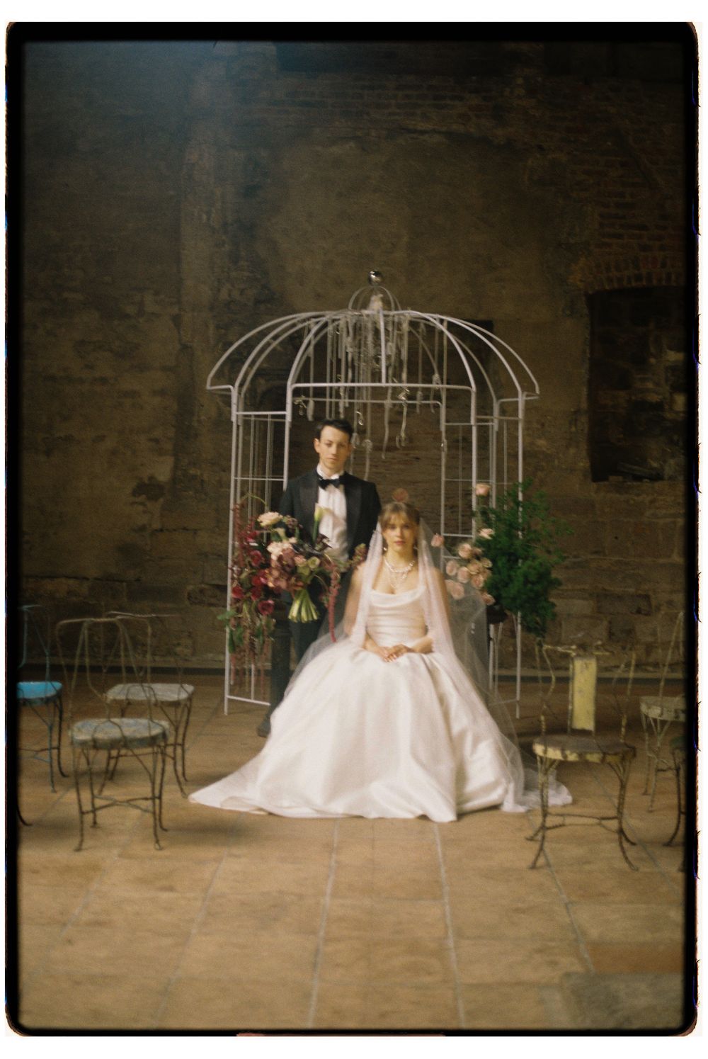 A wedding photo series featuring a bride and groom in an industrial space with decorative white metal garden arches.