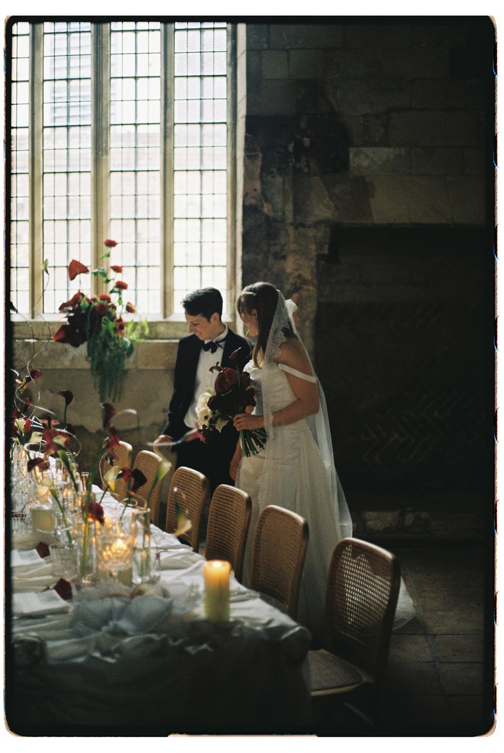 A romantic wedding reception table setting in a historic venue with candlelight and elegant floral arrangements.