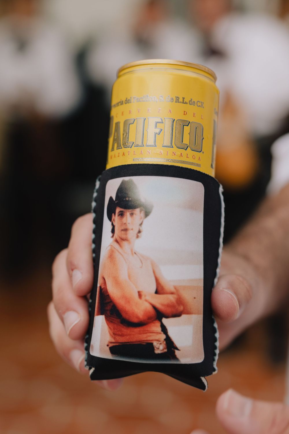 Hand holding a Pacifico beer can in a custom koozie featuring a photo of a man in a cowboy hat.