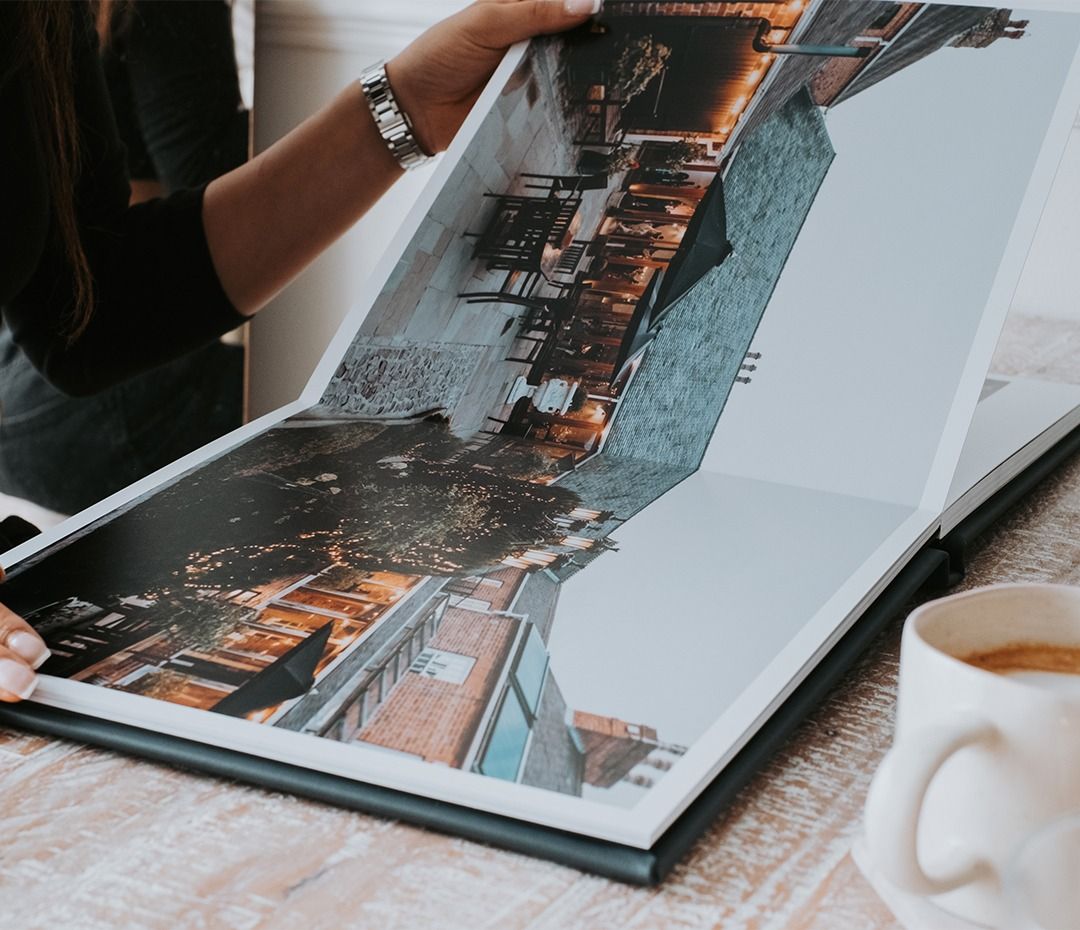 Wedding photo album being viewed on textured surface with coffee cup nearby.