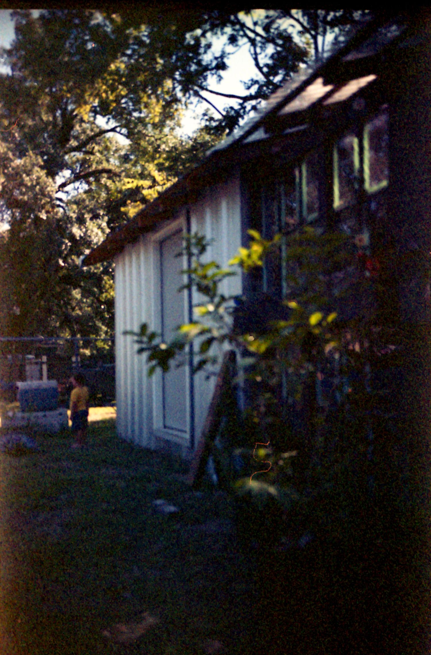 White house exterior with dark shadows and trees at dusk creates a moody residential scene.