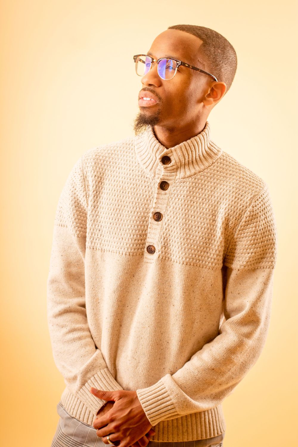 Casual portrait series showing someone in a cream knit sweater against a warm orange background.