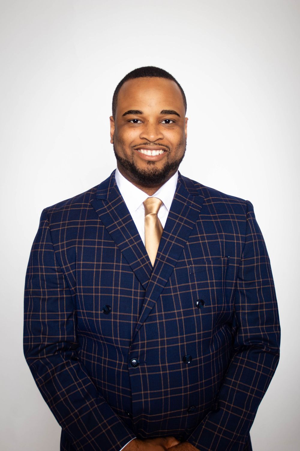 Professional headshots featuring a person wearing a navy windowpane suit against a white backdrop.