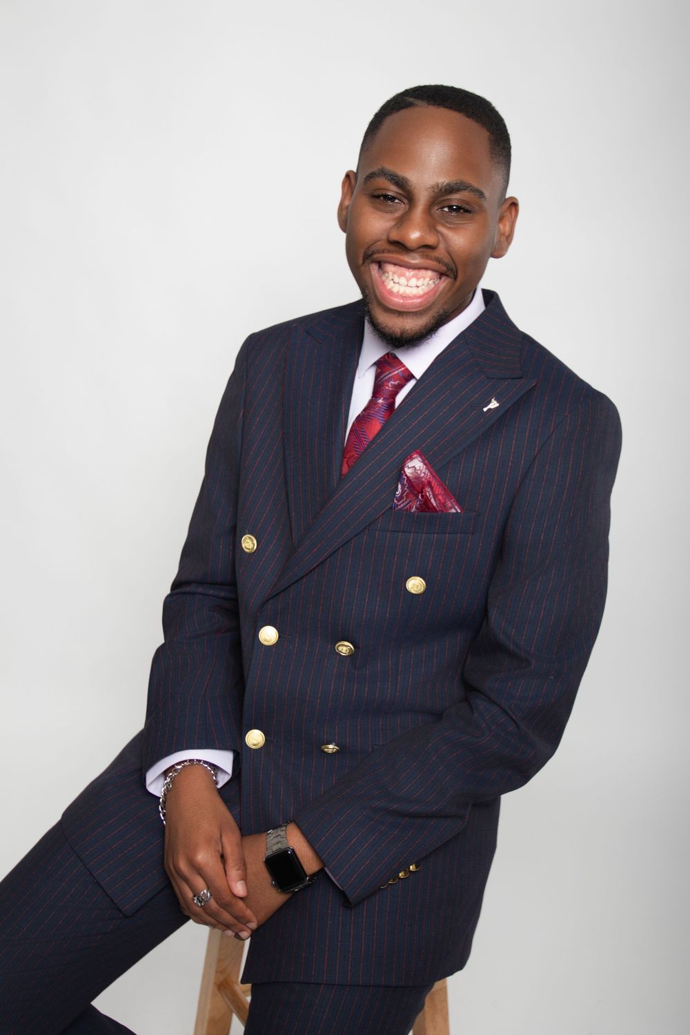 Business portraits showing navy pinstripe suit with gold buttons and red accessories.