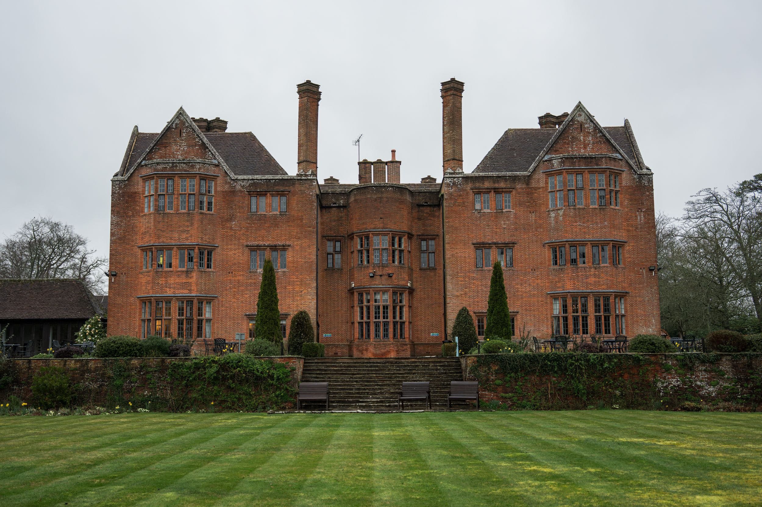 Panoramic view of a grand red brick manor house with Tudor-style architecture.