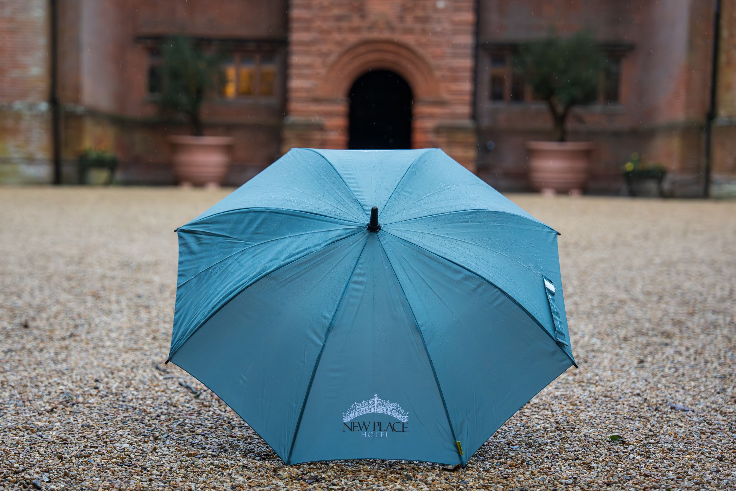A line of bright blue umbrellas arranged on a brick courtyard.
