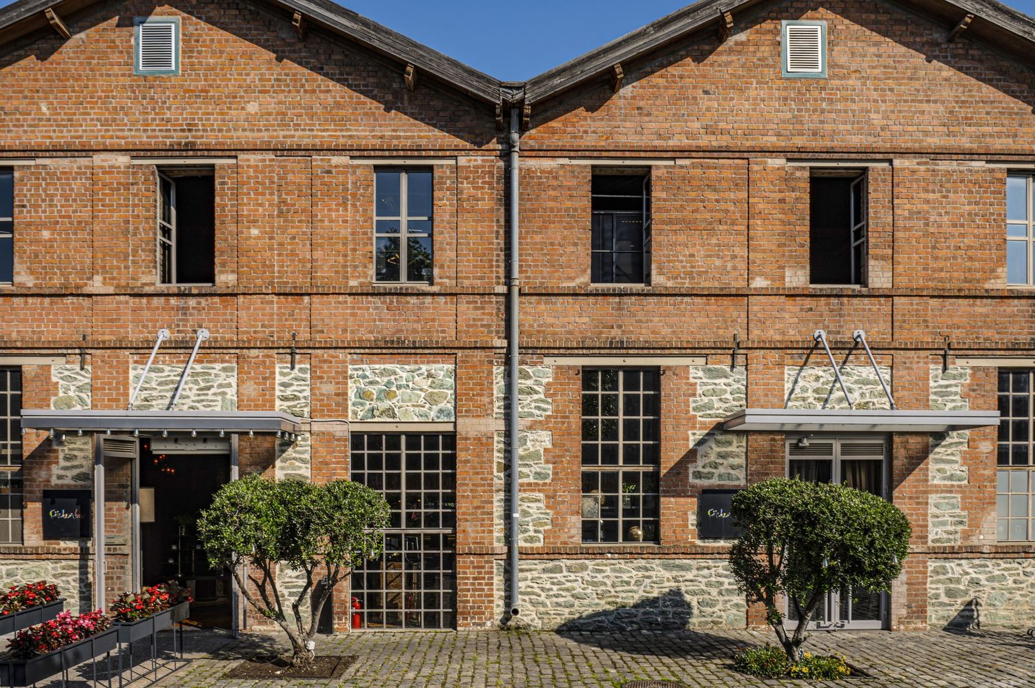 Historic brick warehouse building with multiple arched windows and industrial architectural details in a panoramic view.