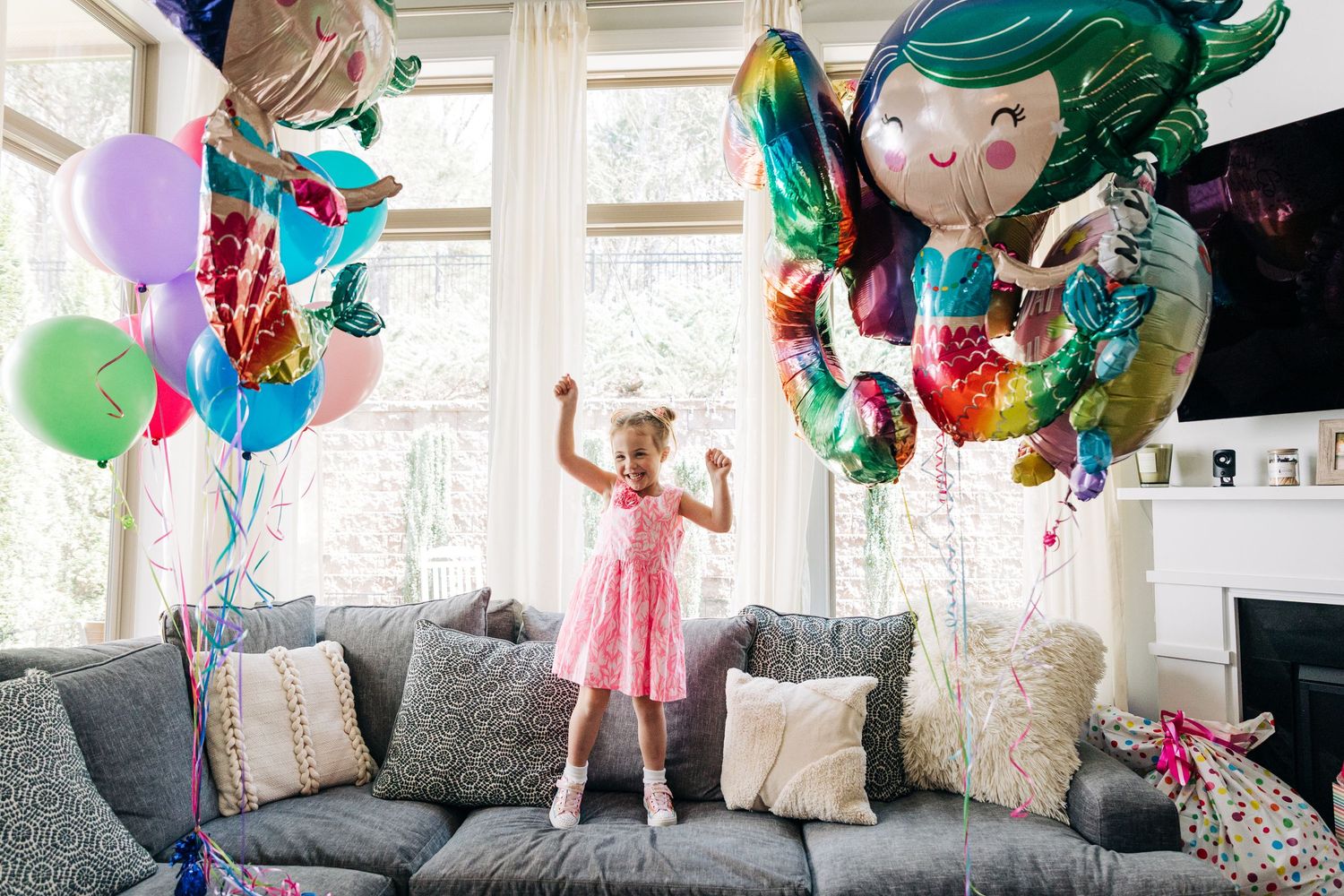 A  birthday scene with colorful balloons, decorations, and festive moments in a bright indoor setting with little girl dancing on a couch