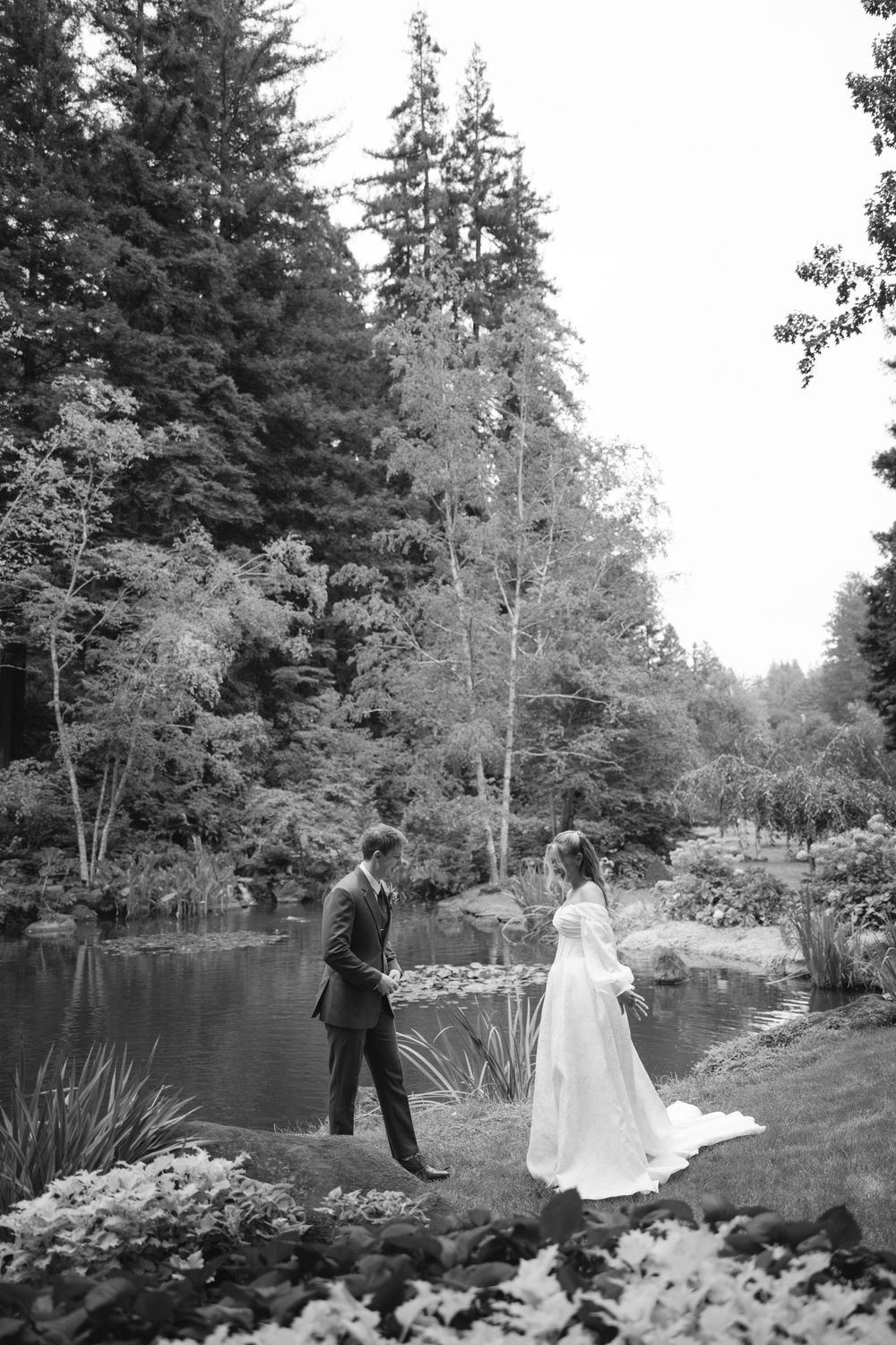 A romantic wedding photo sequence by a serene pond with tall evergreen trees in the background.