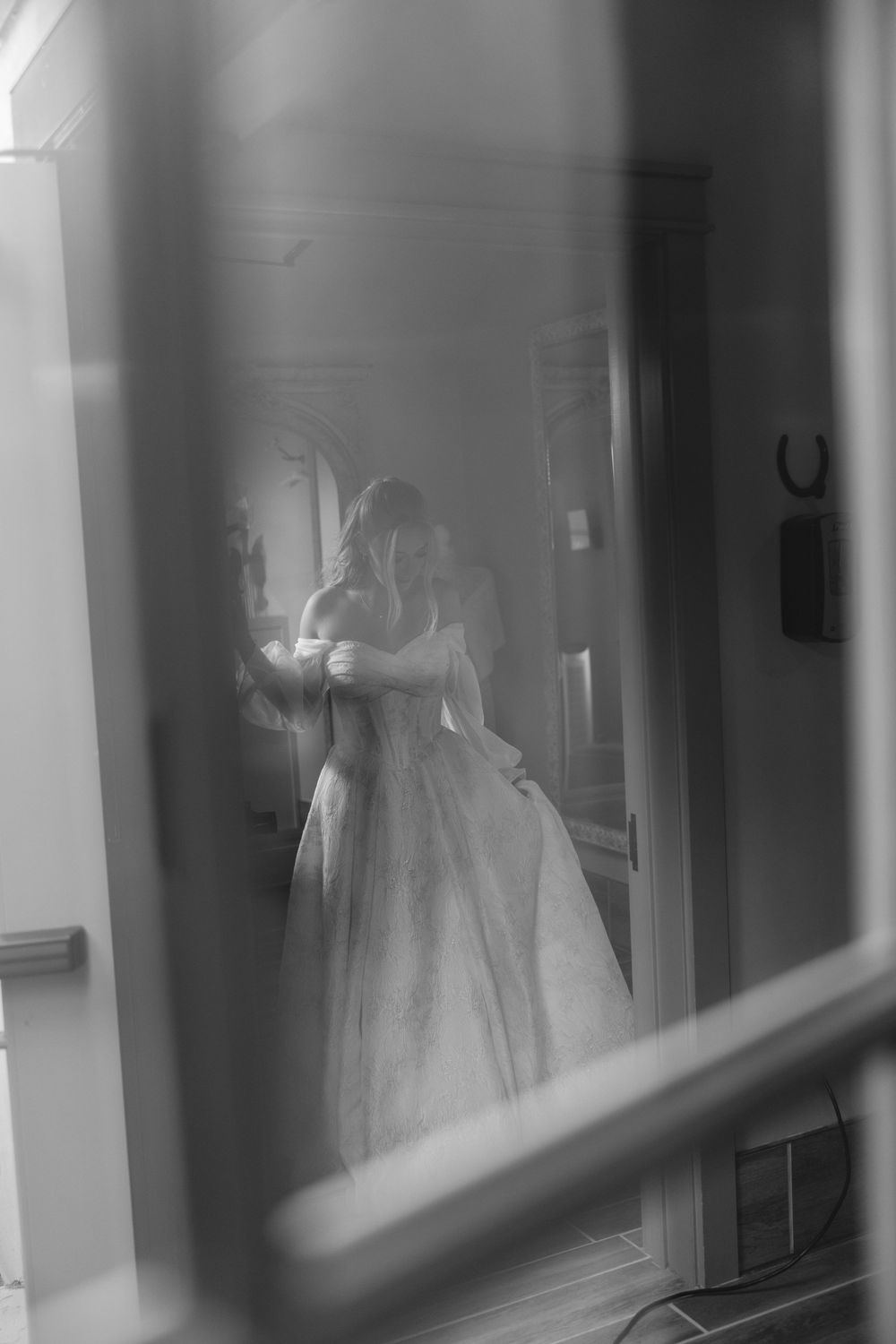 Black and white photograph of wedding dresses displayed in illuminated window cases.