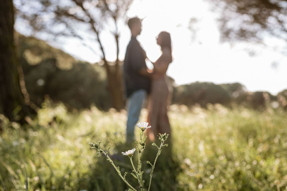 Creative shallow depth of field photo with wildflowers and blurred couple during engagement photoshoot in Lagoa de Albufeira