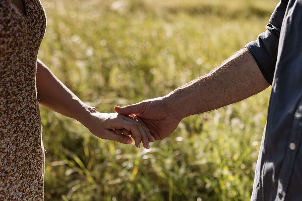 Engaged couple walking dog in tall grass at sunset during pre wedding session in Lagoa de Albufeira Sesimbra
