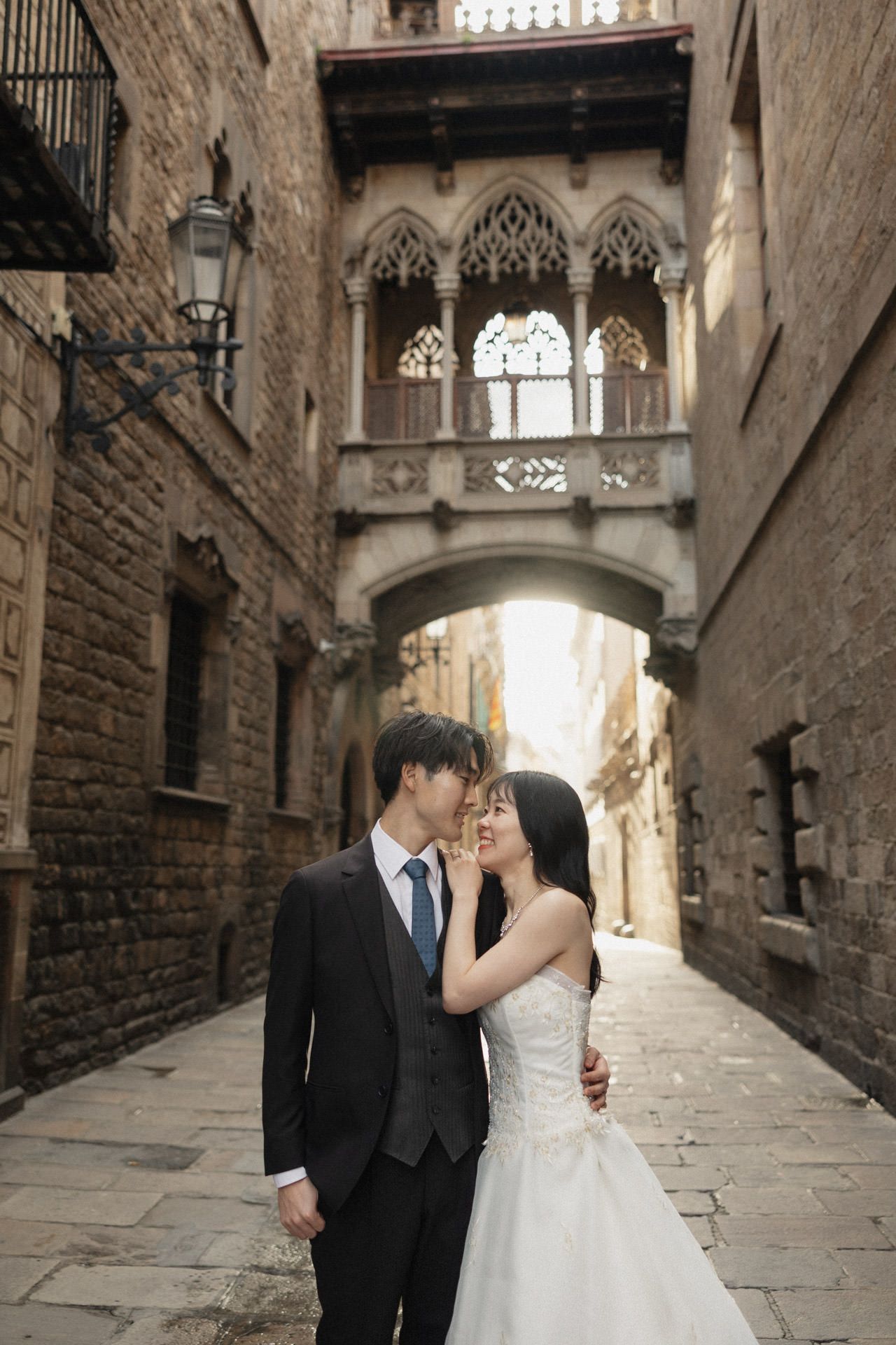 Romantic couple shares intimate moments in a historic stone alleyway with Gothic architectural details.