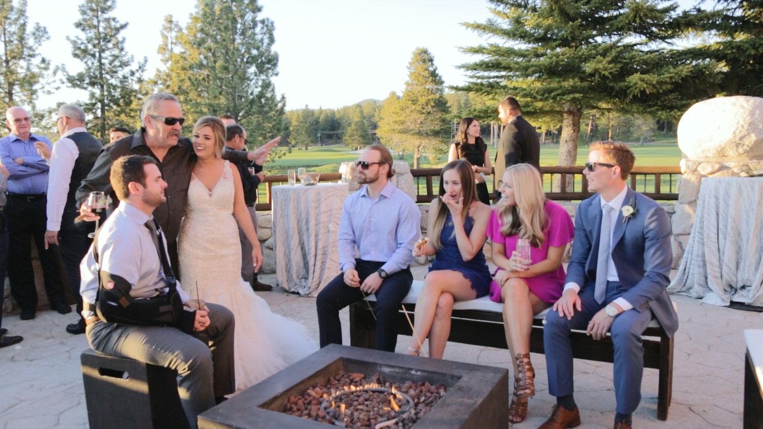 Bride in white gown socializing with wedding guests on outdoor patio at golf course reception.