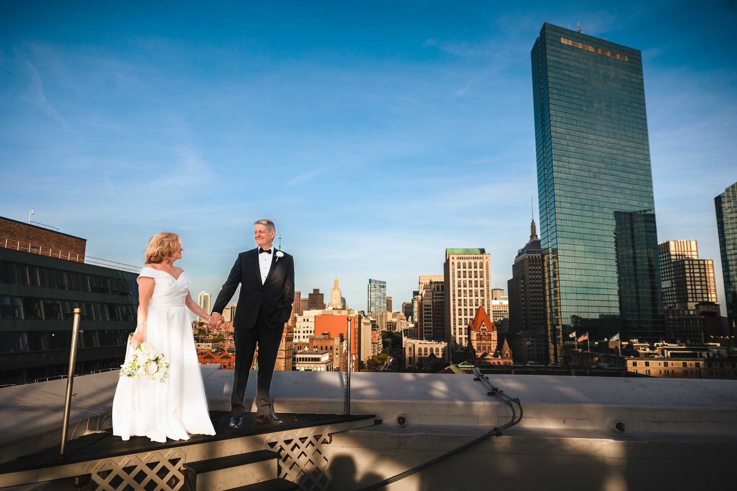 Wedding portraits on rooftop at Lenox Hotel Boston with couple overlooking Boston skyline at golden hour