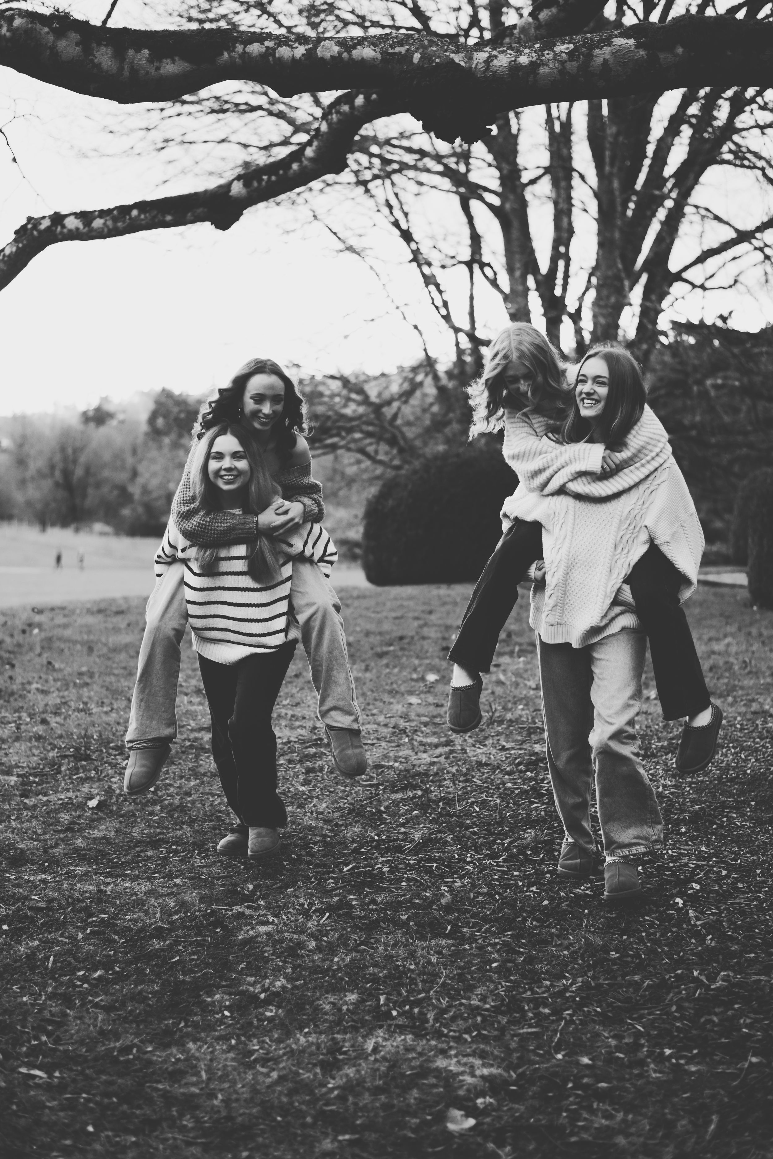 Black and white photos show a couple playfully running and laughing together in a park with bare trees in the background.