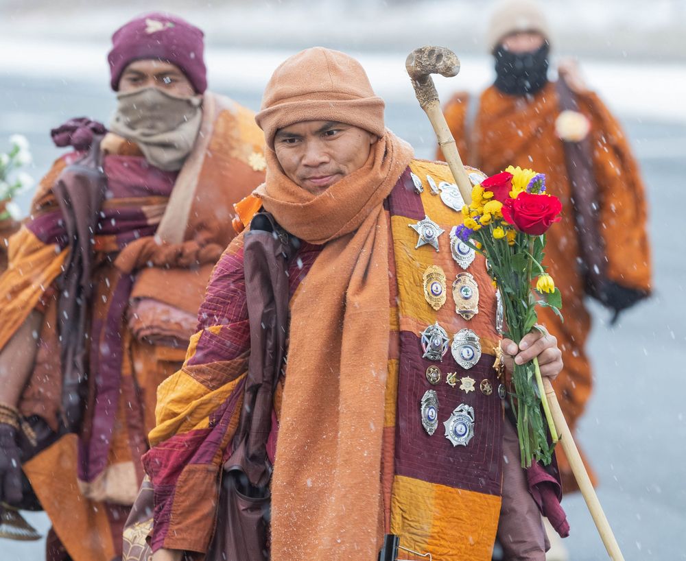 Group wearing traditional clothing and carrying decorative flags during a cultural ceremony.
