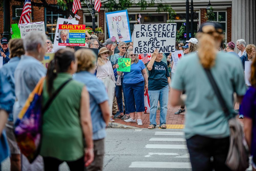 Street protest with demonstrators holding signs and gathering in an urban area.